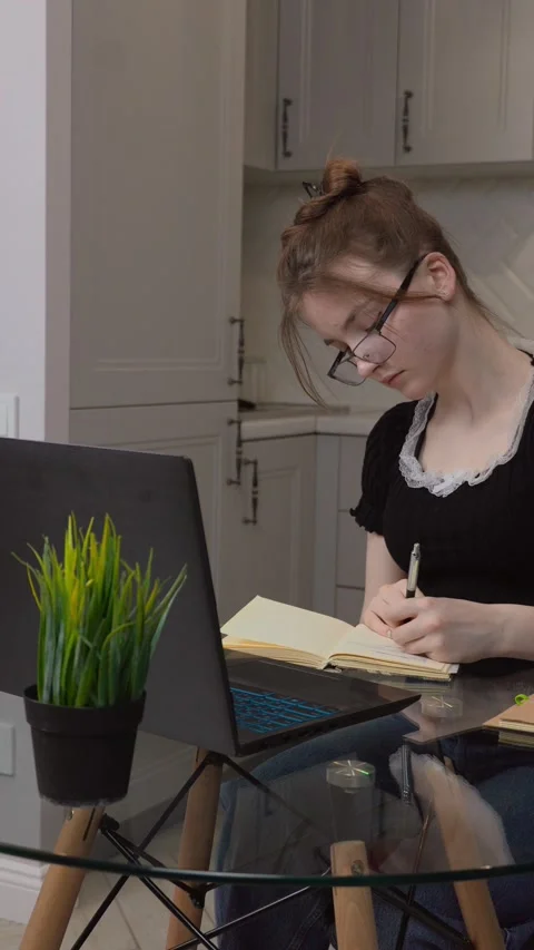 Young woman taking notes while studying from home Stock Footage 311780144