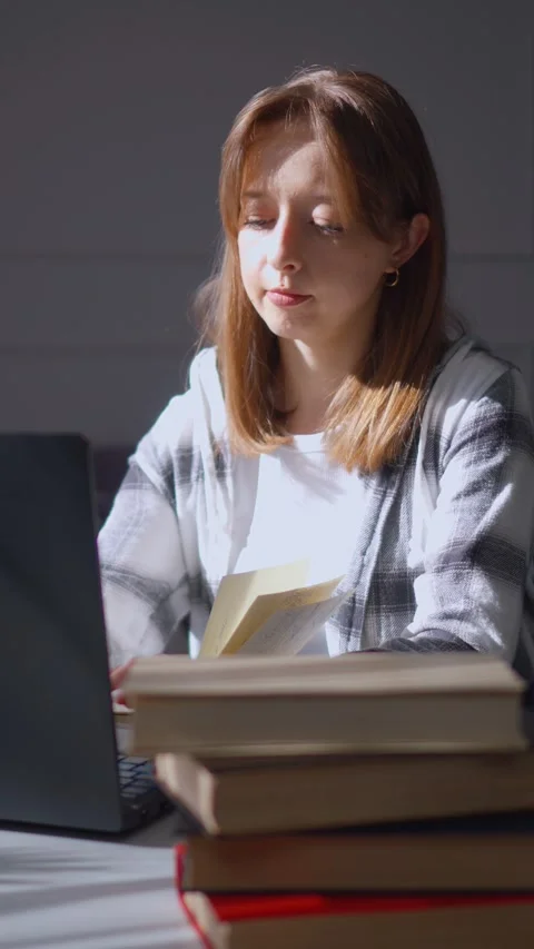 Young woman taking notes while studying on laptop at home Stock Footage 314611268