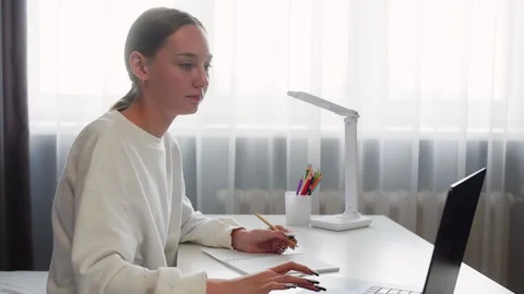 Young woman taking notes while studying on her laptop Stock Footage 315174977