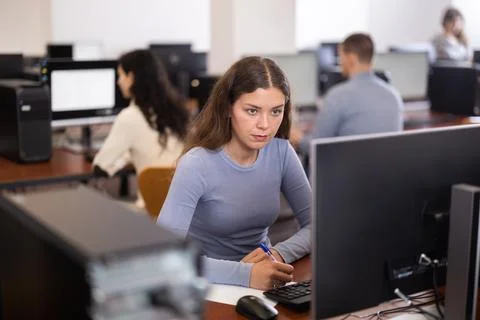 Young woman taking notes while working at computer Foto stock