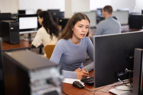 Young woman taking notes while working at computer 스톡 사진