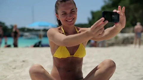 Young woman taking photo with cellphone on the beach, dolly shot Stock Footage