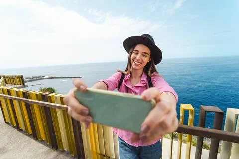 Young woman taking selfie with mobile smartphone during city excursion Stock Photos