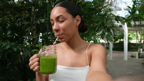 Young woman taking a selfie while drinking green smoothie Stock Footage 344728063