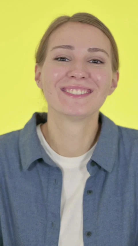 Young Woman Talking on Online Video Call on Yellow Background, Vertical Video Stock Footage 340039341