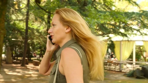 Young woman is talking on the phone on the run, she is in a hurry. 4k, slow Stock Footage