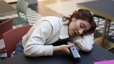 Young woman talks to artificial intelligence while exhausted in cafe Stock Footage 323738637