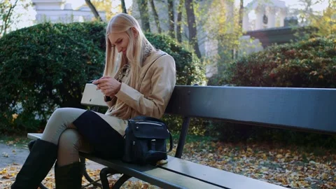 Young woman texting on smartphone while sitting on park bench Video stock 340738906