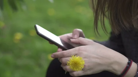 Young Woman Texting while Holding a Yellow Flower at a Park, Spring Time, Slo 動画素材 106791153