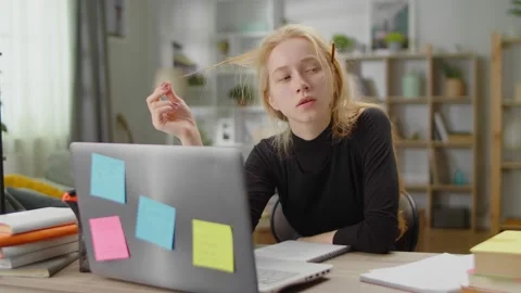 Young woman thinking about solving a problem while studying at home in living Stock Footage 142582521