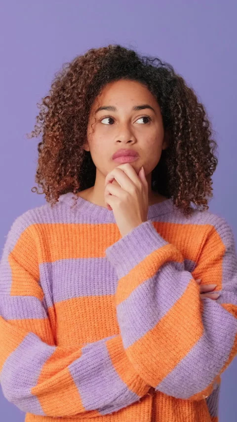 Young woman thinking, making choice on lilac background in studio Stock Footage 291528595