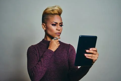 Young woman thinking while Using Tablet device Against Gray Background Stock Photos