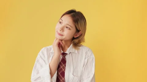 Young woman thinks something isolated on yellow background in studio Stock Footage 258454805