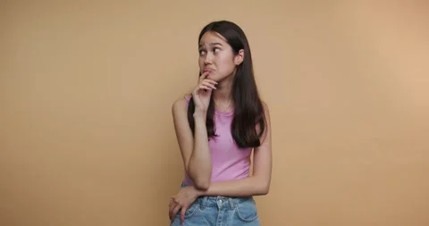 Young woman thinks while posing in different ways against a plain backgroun.. Stock Footage 331989959