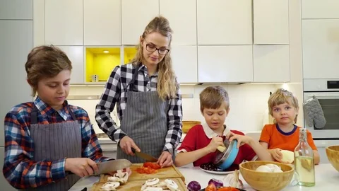 Young woman with three children cutting vegetables for pizza. Stock Footage