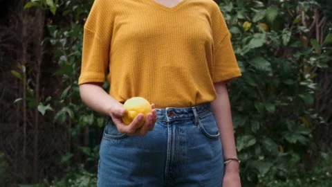 Young woman throwing a lemon into the air in the garden. Stock Footage