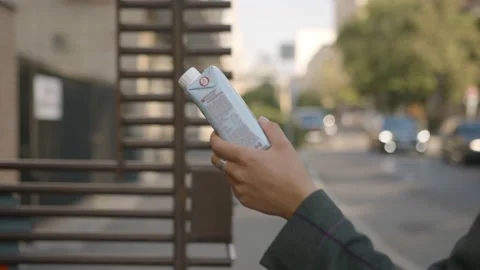 Young woman throws packaging into large trash can on street Stock Footage 144488655