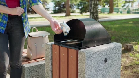 Young woman throws plastic wrapper in trash bin outdoor Stock Footage 154952827