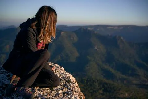 Young woman on the top of a mountain staring at the horizon. Stock Photos