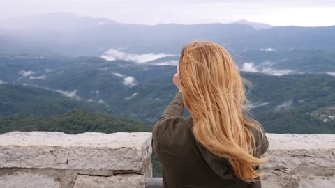 Young woman at the top of the mountain taking a selfie in slow-motion. Young Stock Footage