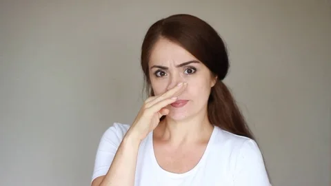 A young woman touches her nose with her hand and scratches. Allergy, virus Stock Footage