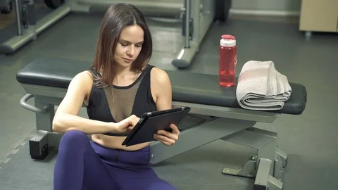 Young woman trainer making exercise plan using tablet computer in the gym Stock Footage 123583704