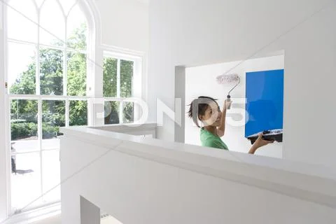 Young woman with tray and roller painting wall, smiling, portrait Stock Photos