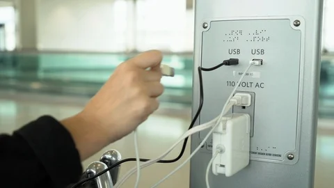 Young woman trying to plug in device at charging station at airport Stock Footage 122172906