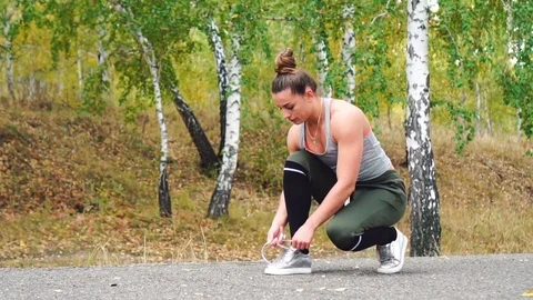 Young woman tying running shoes before run Stock Footage