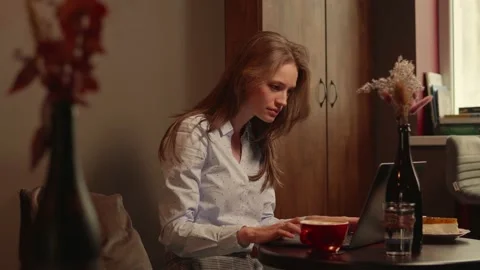 Young woman typing on a computer in a cafe Stock Footage 169417072