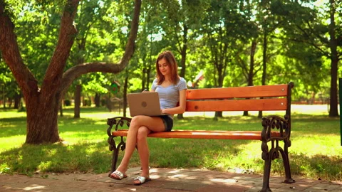 Young woman typing on computer sitting on the bench Stock Footage 150204689