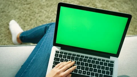 Young woman typing on laptop computer keyboard with green screen while sitting Stock Footage 76356161