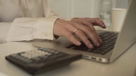 A young woman typing on a laptop keyboard Stock Footage