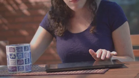 Young woman typing on tablet while drinking coffee Stock Footage 80384119