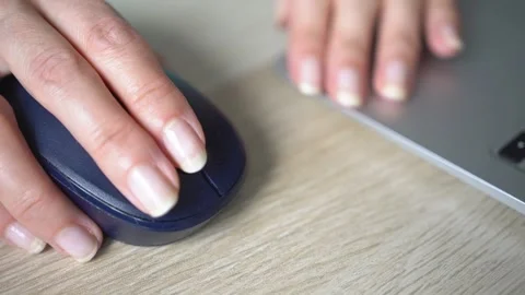 A young woman uses a computer mouse while working on a laptop. Stock Footage 342785675