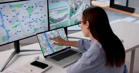Young Woman Uses Computer Software To Study Detailed Urban Land Map. Stock Photos