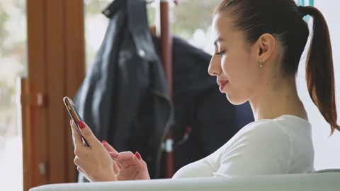 A young woman uses a smartphone while sitting on the sofa in the reception area Stock Footage 196924679