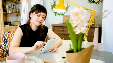 Young woman uses a tablet while relaxing at home at the table 動画素材 127615335