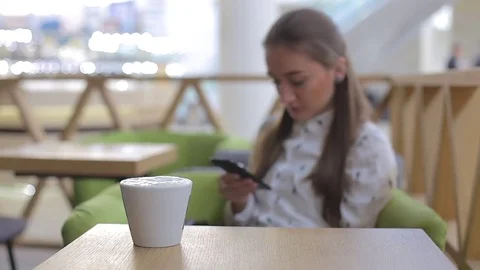 Young woman using app on mobile phone in cafe writes text message on smartphone Stock Footage 75608674