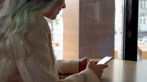 Young woman using app on smartphone in cafe and texting on mobile phone Stock Footage 78377508