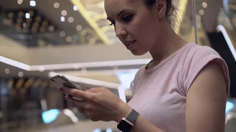 Young woman using app in the smartphone in a moving elevator with bright lights Stock Footage 78605208