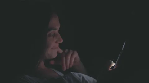 Young woman using cellphone on bed at night Stock Footage 82371384