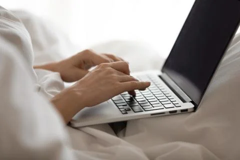 Young woman using computer in bed after waking up. Stock Photos