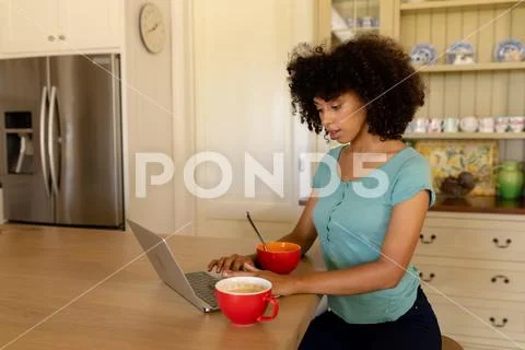 Young woman using computer in the kitchen Stock-Fotos