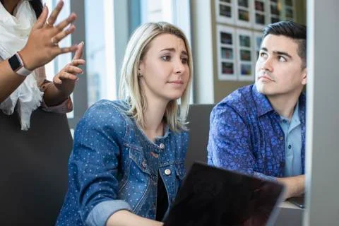 Young woman using computer in office, showing co-workers something on her screen Foto stock