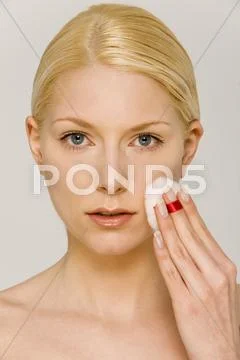 Young Woman Using Cotton Pad On Face, Portrait