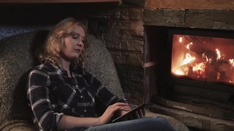 Young Woman Using Digital Tablet Sitting By Fireplace at Home Stock Footage 72139077