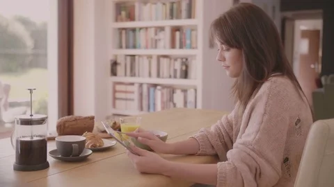 Young woman using digital tablet at breakfast table Video stock 79659170
