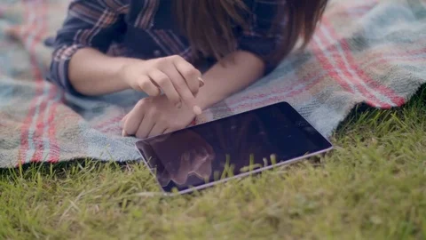 Young woman using digital tablet while lying at park Stock Footage 79659310