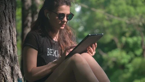Young woman is using digital tablet in park 스톡 동영상 105005026